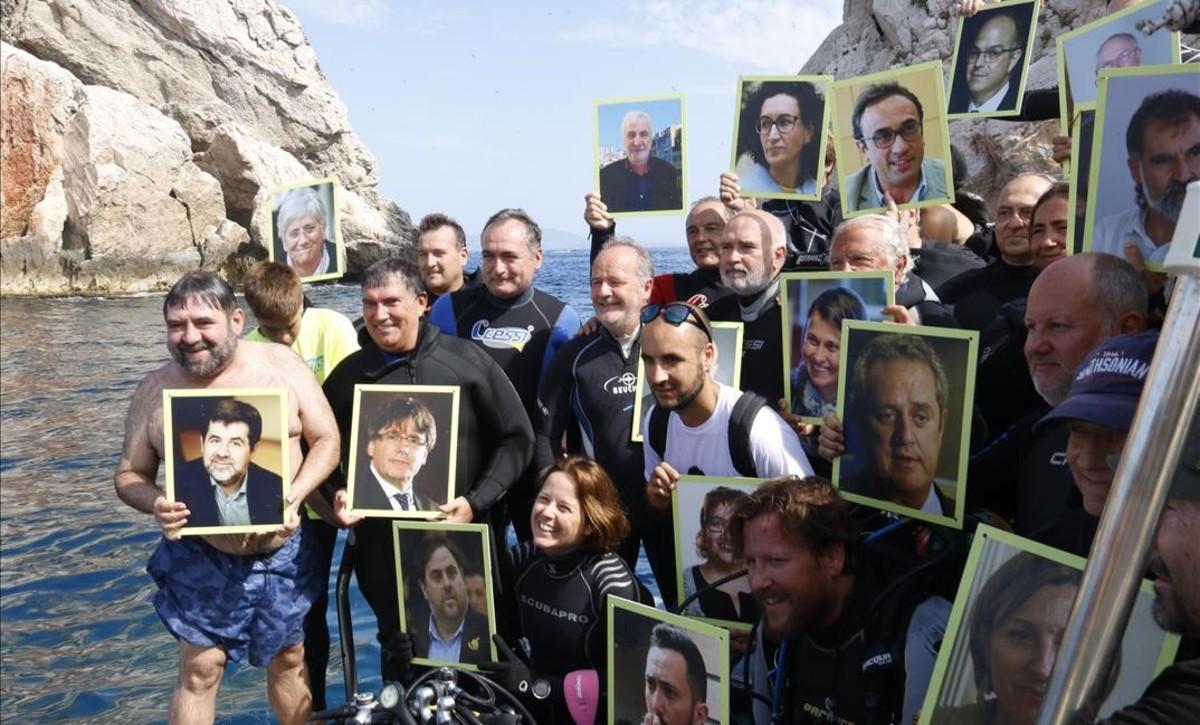 Submarinistas sostienen fotos de los políticos presos y en el exilio, en las Illes Medes.