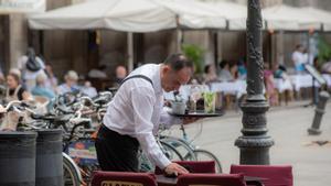 Un camarero limpia una mesa en la Plaza Real de Barcelona.