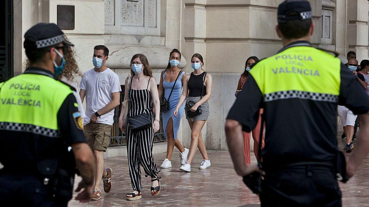 Policías locales controlan en València el uso de la mascarilla en los primeros días de obligatoriedad. | F. BUSTAMANTE