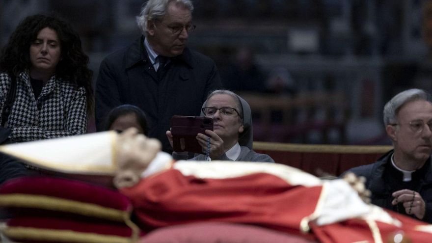 Una religiosa fotografía a Benedicto XVI en su capilla ardiente. | Efe