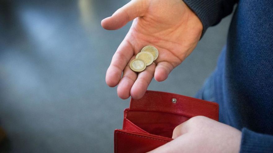 Un hombre guarda unas monedas en una cartera.