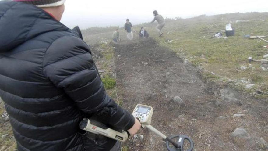 Una arqueóloga busca restos en L.lagüezos con un teledetector de metales.