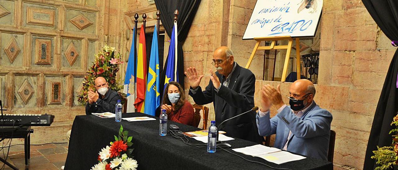 Arriba, Claudio Menéndez, de pie, recibe una ovación, flanqueado por Manuel Fernández y Elsa Suárez. Junto a ella, a la izquierda, Javier Marinas. En el círculo, Pipo Prendes, que actuó en el acto. Debajo, público asistente. | B.G.