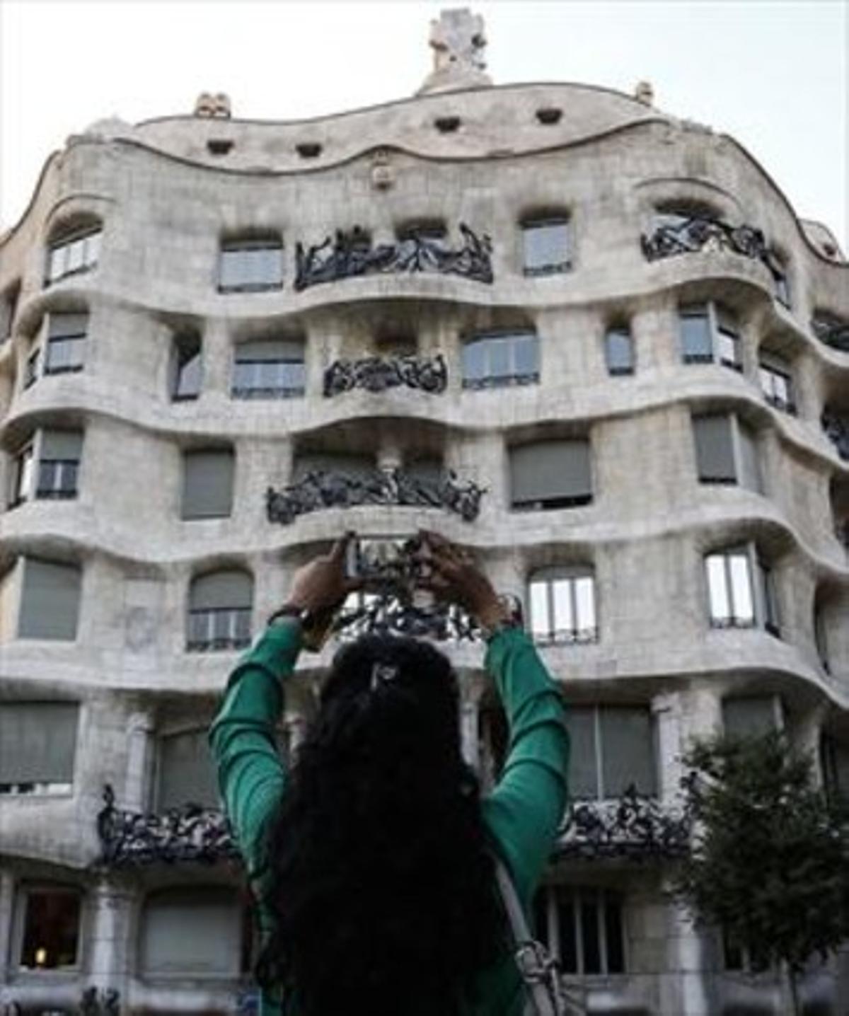 Una turista fotografia la Pedrera de Gaudí, la façana de la qual està registrada com a marca.