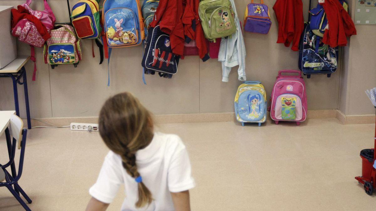 Una niña, de espaldas en un colegio.