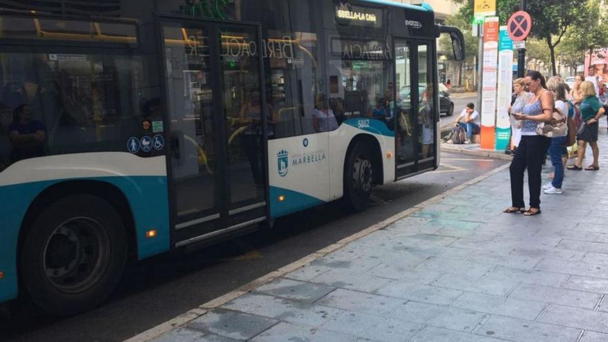 Usuarios en una de las paradas del centro urbano de Marbella junto a un autobús.