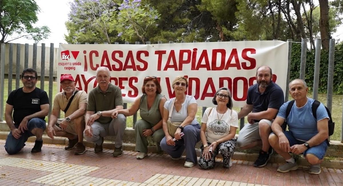 Representantes de EU, ante las viviendas, con una pancarta que reza "Casa tapiadas, mayores olvidados"