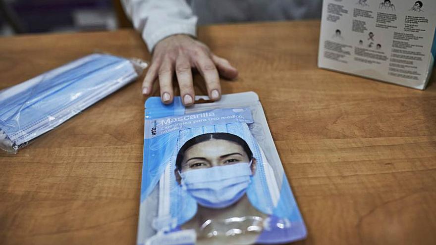 Una farmacéutica muestra un paquete de mascarillas. |   // E.P.