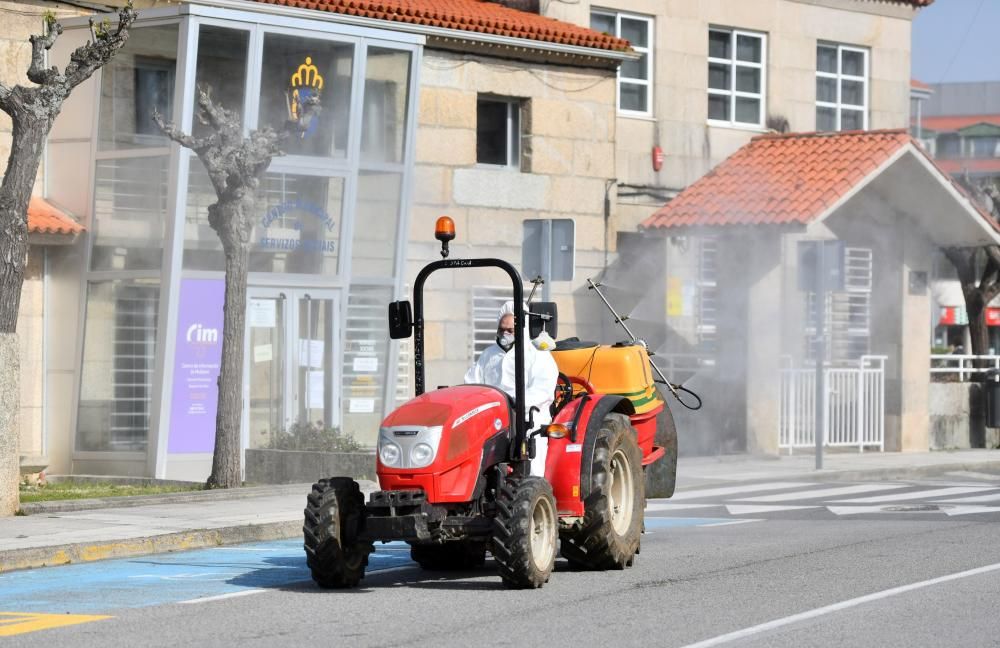 Subidos en un tractor y cargados de desinfectante en sus fumigadoras trabajan desde ayer los vecinos de Sanxenxo en la limpieza del municipio. // Gustavo Santos