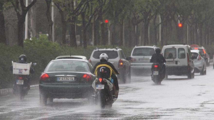 Usuarios de la moto un día lluvioso en la Gran Vía Marqués del Turia.