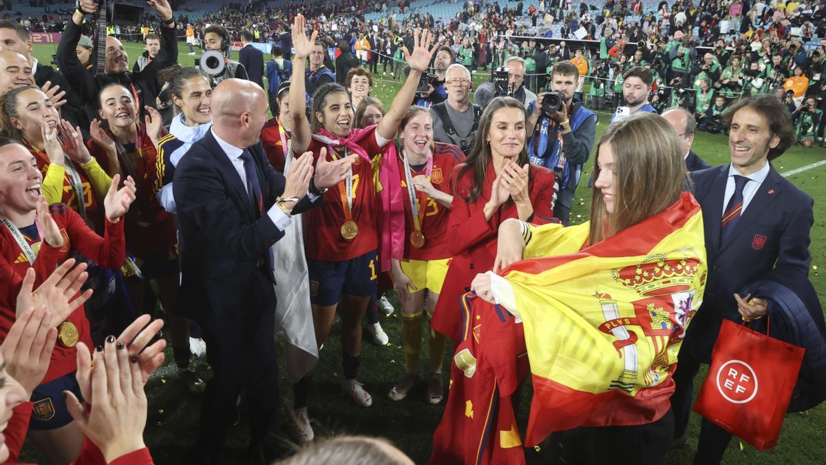 La Infanta Sofía, envuelta en la bandera de España y junto a su madre, la Reina Letizia, celebra el triunfo de la selección nacional femenina junto a las jugadoras y los técnicos sobre el césped del Accor Stadium, en Sidney (Australia).