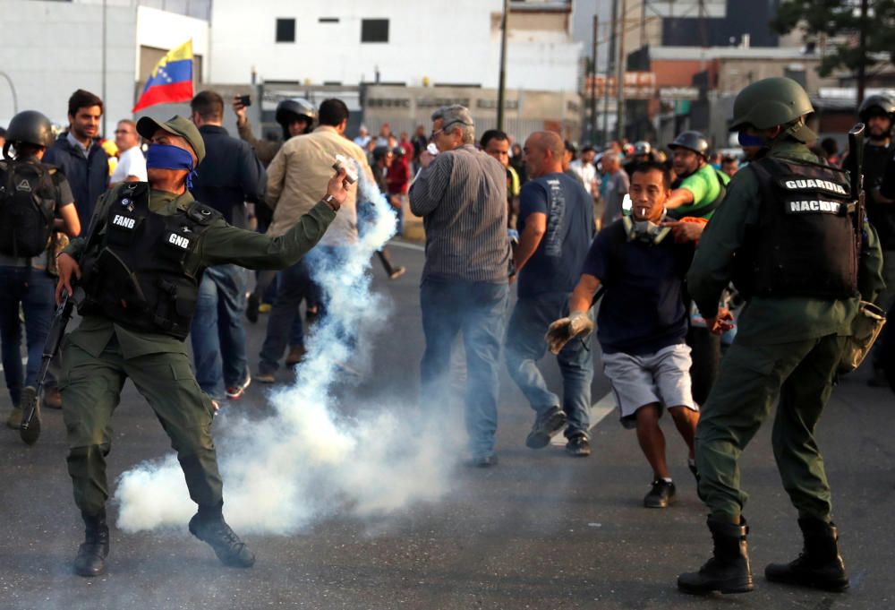 A military member throws a tear gas canister ...