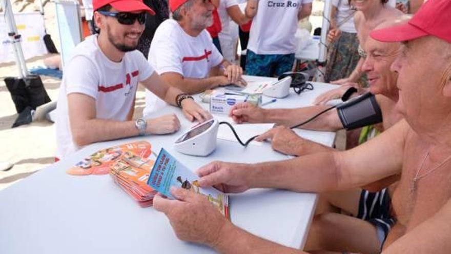 Los voluntarios de Cruz Roja toman la tensión a personas mayores ayer en el Postiguet.