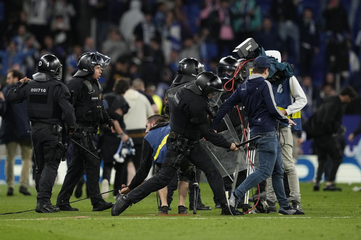 Spanish National Police officers try to stop some Espanyol fans who invaded the field after the Spanish LaLiga soccer match against FC Barcelona at RCDE Stadium in Barcelona, Catalonia, Spain, 14 May 2023. EFE/ Alejandro Garcia