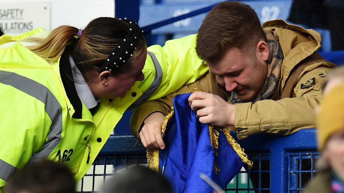 Liverpool (Gran Bretaña): Premier League, Everton - Manchester City. Una asistente en la grada consuela a un fan con la bandera de Ucrania al comienzo del partido probablemente emocionado por la demostración contra la guerra