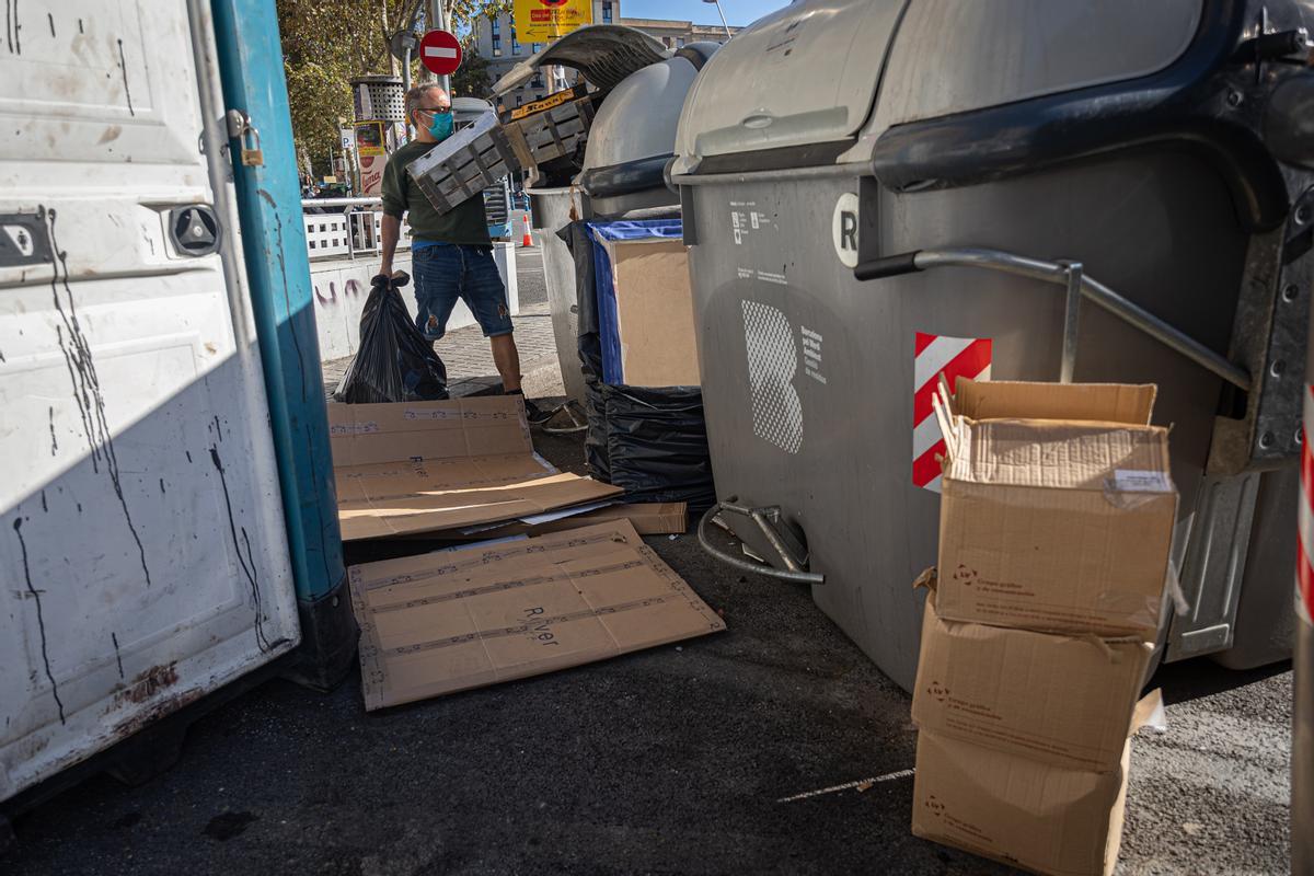 Un hombre tira basura en unos contenedores en el Eixample.