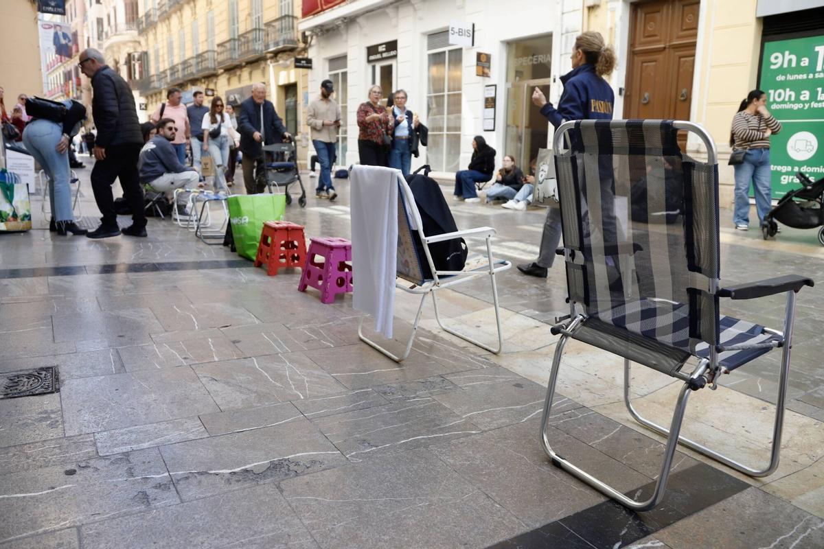 Varias personas esperan sentadas en las calles de la capital con sus propias sillas, para ver las procesiones, donde están prohibidas por un bando del Ayuntamiento de la capital