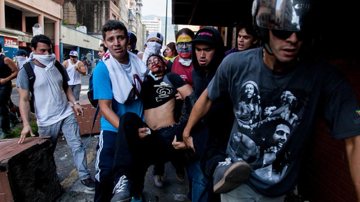 Varios manifestantes trasladan a un joven gravemente herido tras recibir un disparo, este miércoles en Venezuela.