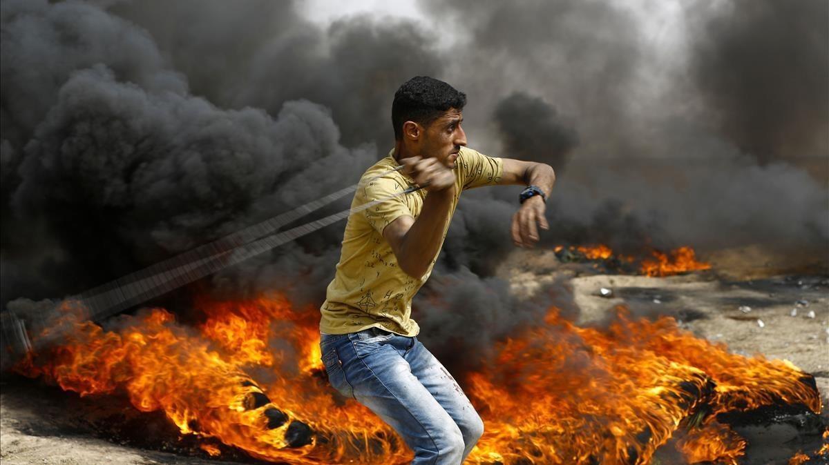 Un palestino se dispone a lanzar piedras entre los neumáticos incendiados contra las tropas israelís, en las protestas junto a la frontera de la Franja de Gaza, el 20 de abril. Un palestino se dispone a lanzar piedras entre los neumáticos incendiados contra las tropas israelís, en las protestas junto a la frontera de la Franja de Gaza, el 20 de abril.