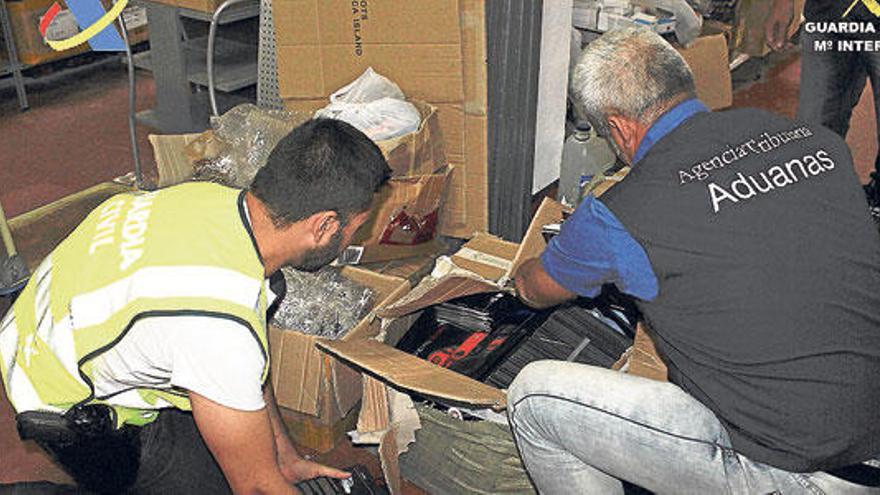 Dos agentes inspeccionan los auriculares intervenidos.