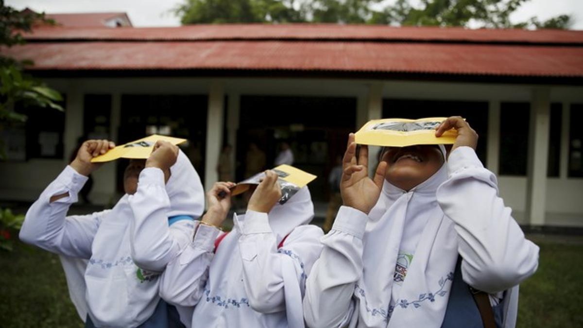 Un grupo de estudiantes prueban unos filtros para observar el eclipse de sol, este lunes en la isla indonesia de Ternate.