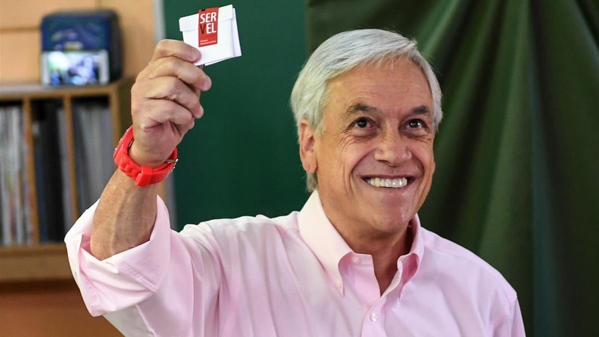 Piñera sonríe mostrando su papeleta, antes de votar, en Santiago de Chile, el 17 de diciembre.