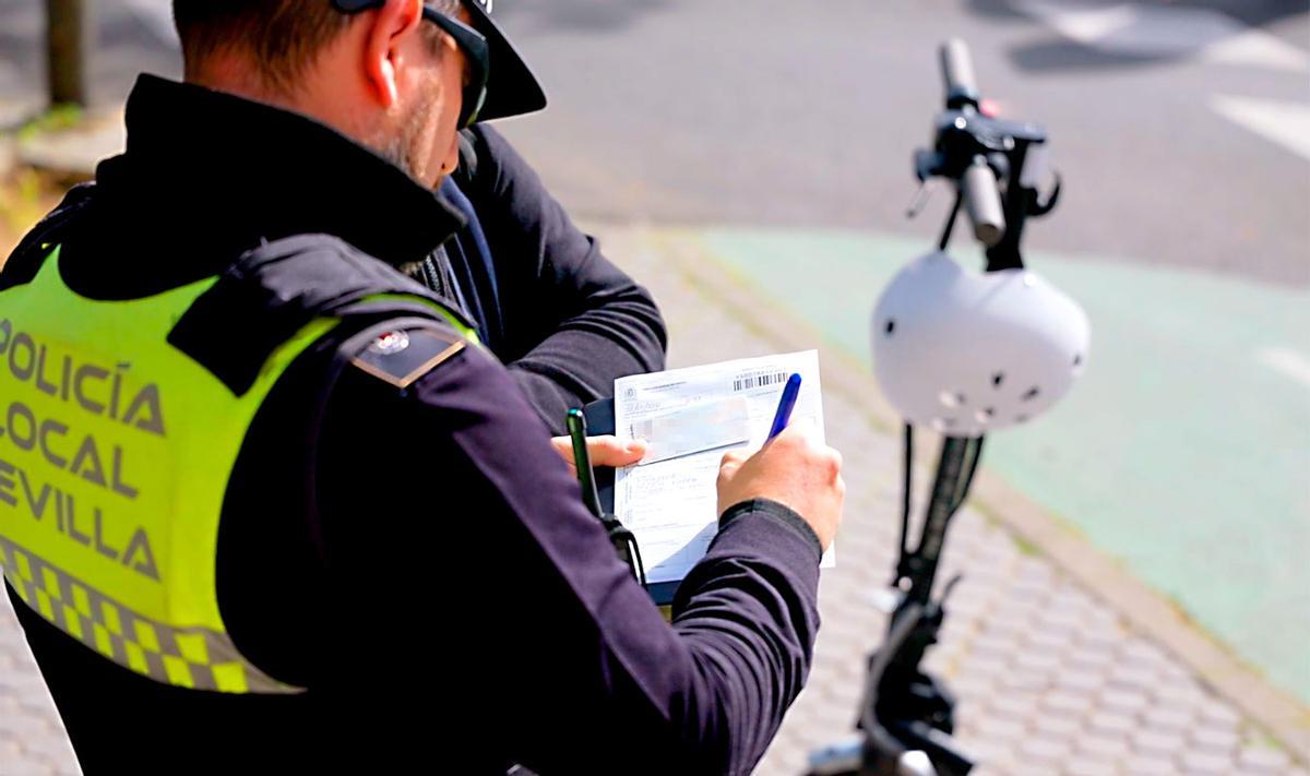 Un agente de la Policía Local sanciona a un usuario de patinete eléctrico.