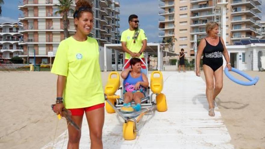 Dos socorristes de la platja de Torre Valentina ajuden la Laura a entrar a l&#039;aigua amb la cadira amfíbia.