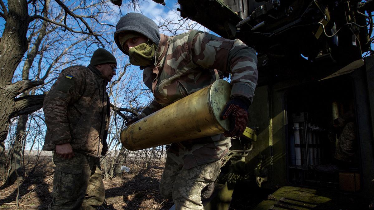 Soldados ucranianos llevan un proyectil, mientras se disponen a disparar hacia las tropas rusas, en Bajmut
