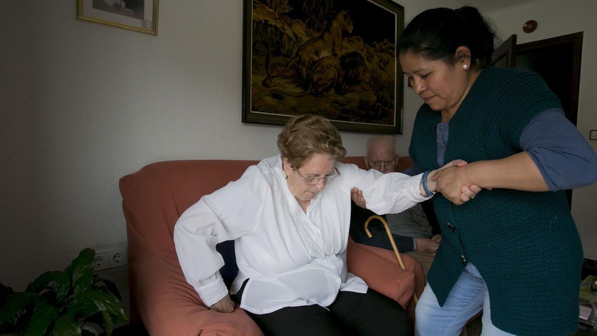 Una pareja de ancianos es atendida por una cuidadora.