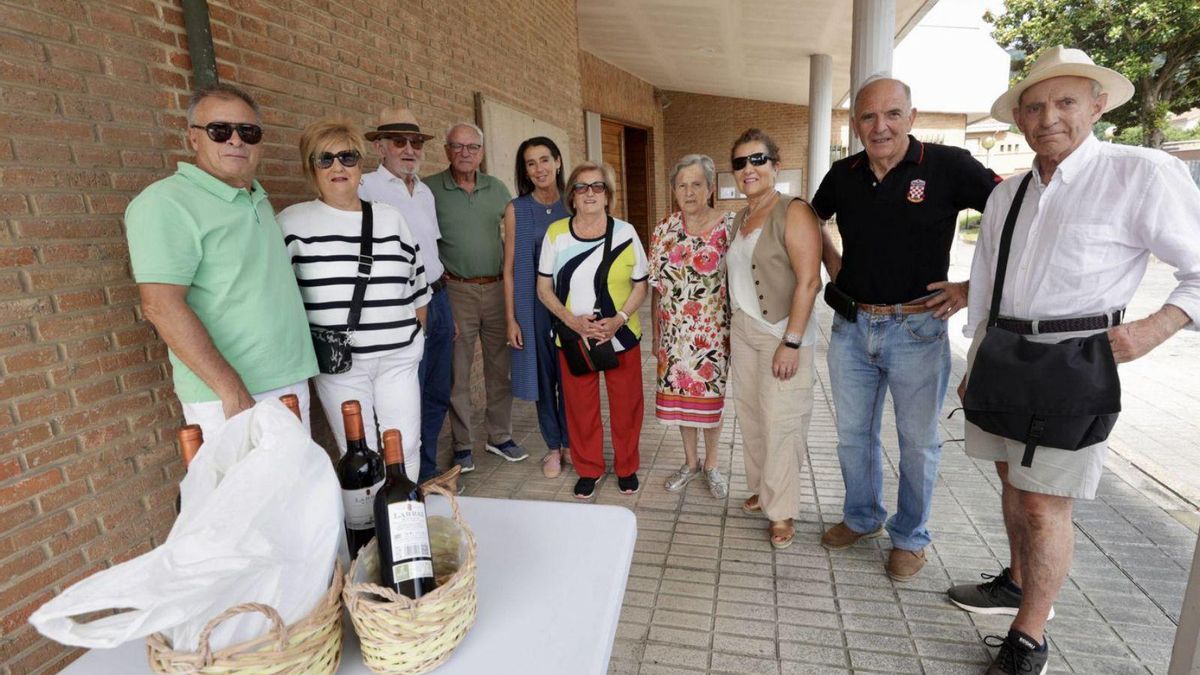 Miembros de la asociación posan con algunos vecinos ante unas botellas de vino. | IRMA COLLÍN