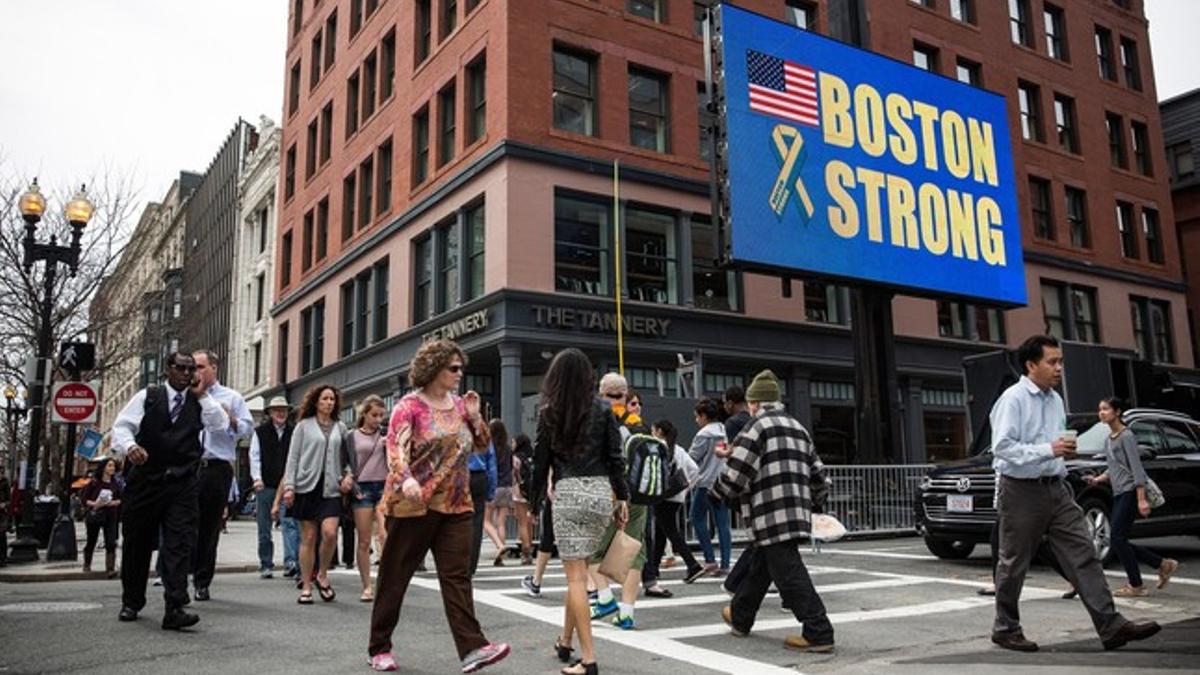 Ciudadanos de Boston, por el centro de la ciudad, este lunes, junto a un cartel que destaca la fortaleza de la ciudad.