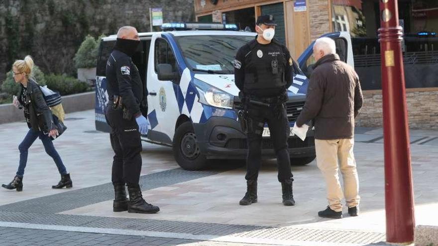 Efectivos policiales conversan con un ciudadano en la vía pública. // R. Grobas