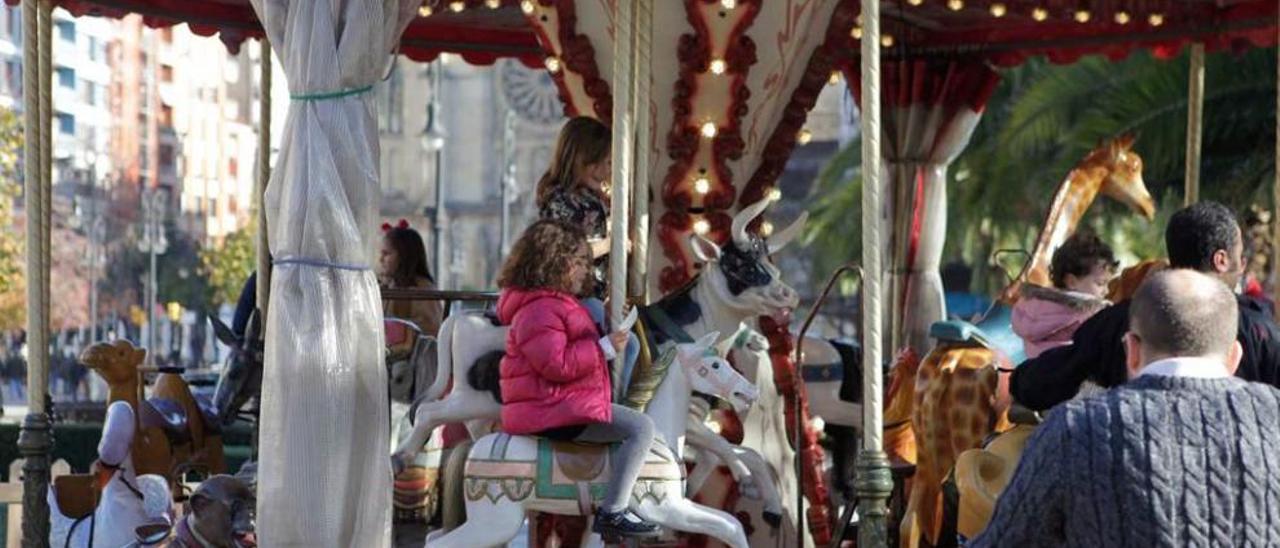 Varios niños en el carrusel de Begoña. A la derecha, el mercado del hotel Asturias.