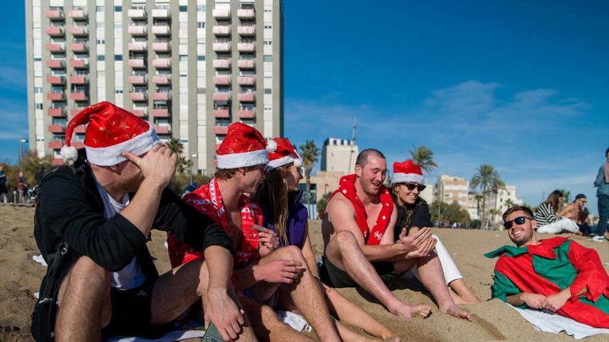 Unos turistas con gorros de Navidad disfrutan de las altas temperaturas en la playa de la Barceloneta, a 25 de diciembre de 2022. Lorena Sopêna / Europa Press