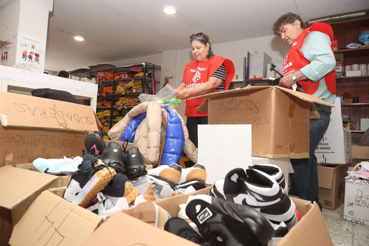 Marta Lucía y Benito, dos veteranos, abriendo cajas y preparando el material, en el local de Cáritas de la calle Pan de Soraluce, en Os Mallos.