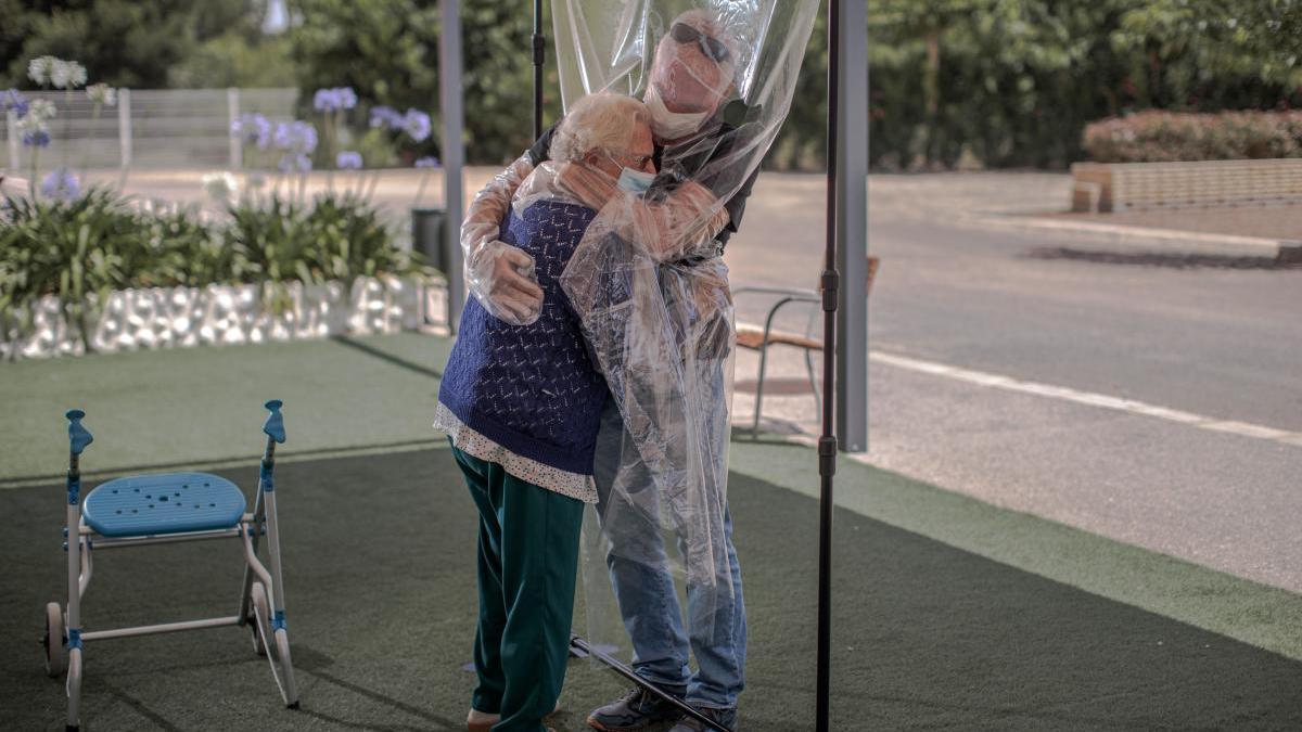 Una interna en una residencia de mayores abraza a su hijo a través de un plástico habilitado para que los familiares se puedan dar su primer abrazo desde hace tres meses.