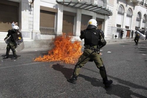 Flames from a molotov cocktail flare up near Greek riot police at a protest march by Greece's Communist party in central Athens during a 24-hour labour strike