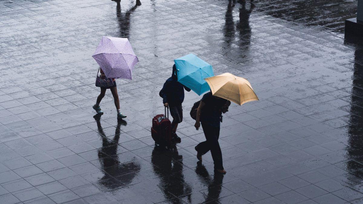 Varias personas caminando bajo la lluvia.