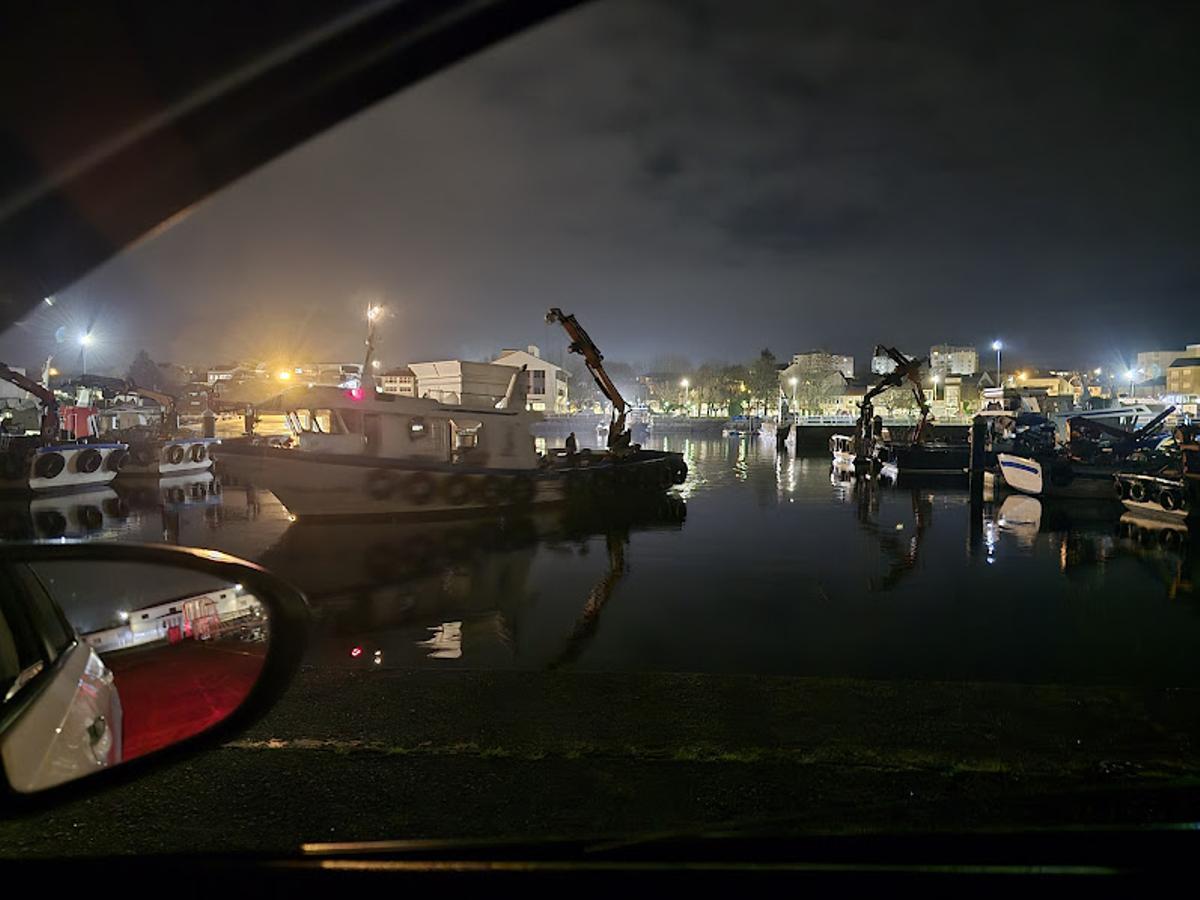 La llegada de un barco auxiliar de acuicultura, ya de noche, al puerto de Vilaxoán.