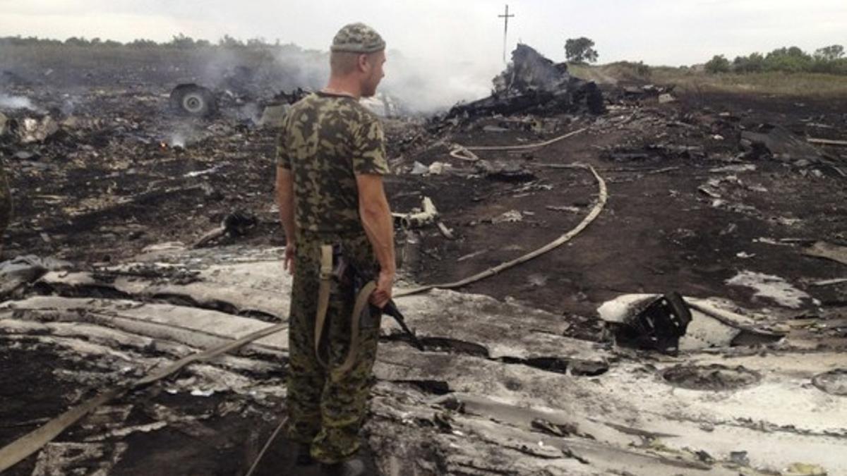 Un separatista prorruso contempla los restos del avión malasio derribado este jueves sobre Ucrania.