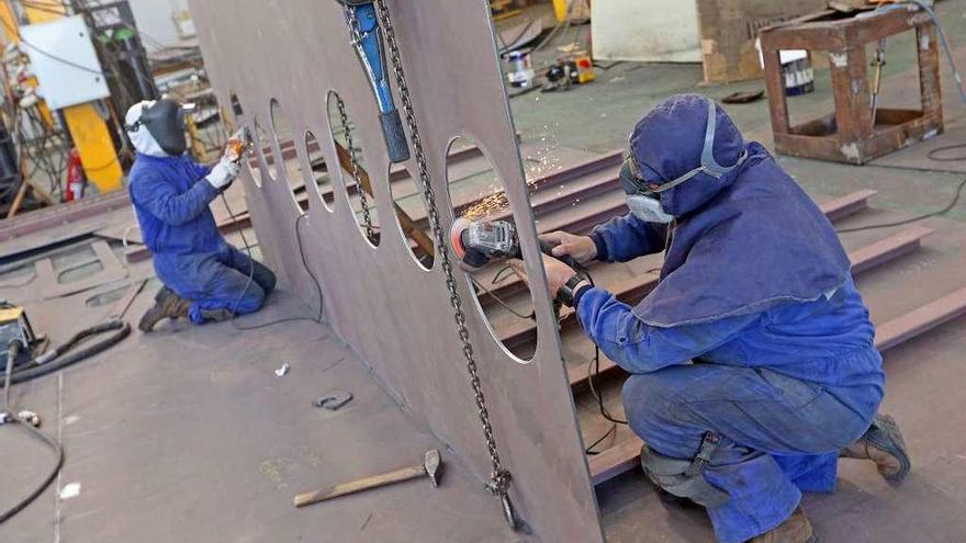 Dos trabajadores cortan chapa en un astillero gallego.