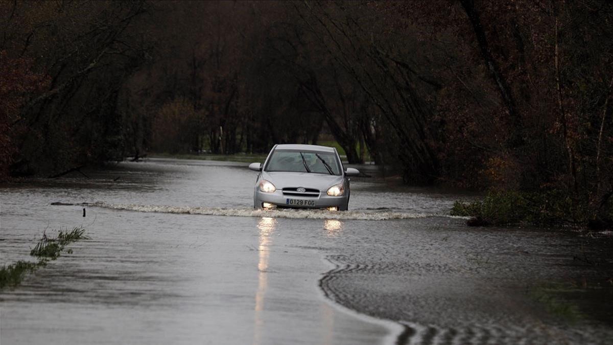 Un coche cruza la carretera inundada LU-P-1701 en la localidad gallega de Muimenta (Lugo), el 19 de diciembre del 2019