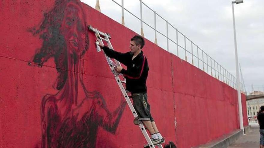 Un grafitero plasma sobre el muro rojo a la «Lloca» de El Rinconín. / marcos león