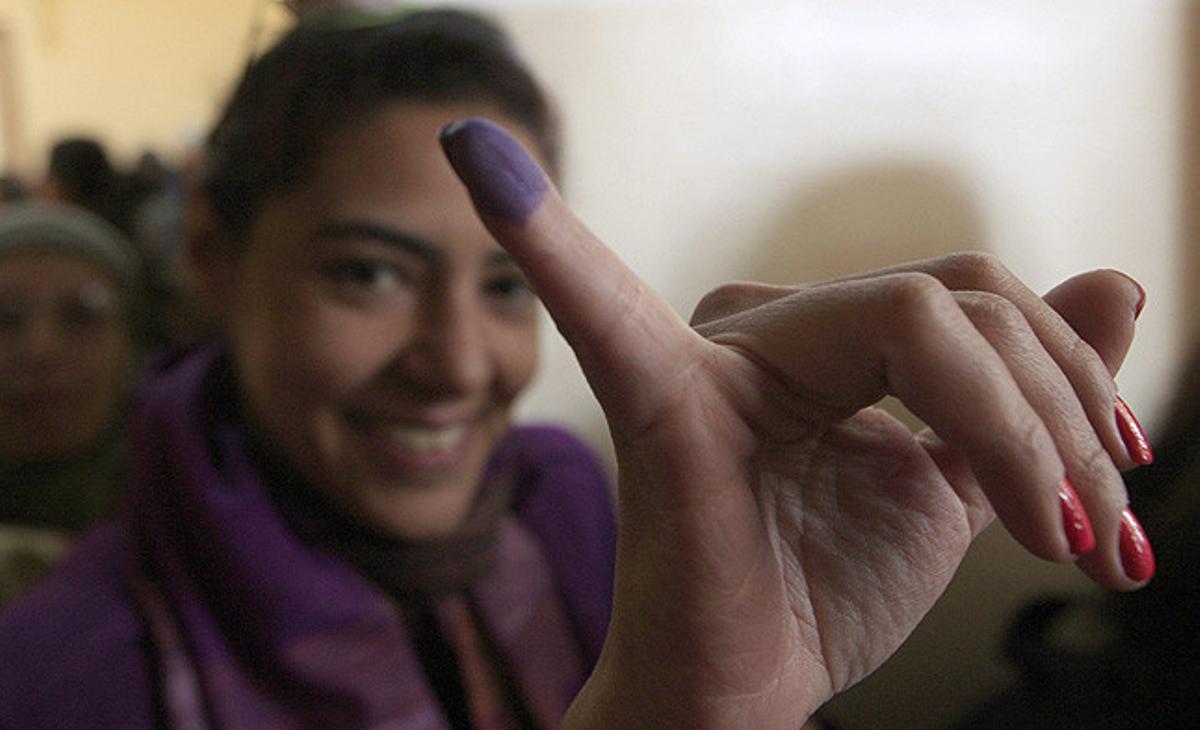 Una dona mostra el seu dit tacat de tinta després d’exercir el vot en la primera ronda de les eleccions legislatives en un col·legi electoral a Kasr al-Aini, el Caire (Egipte).