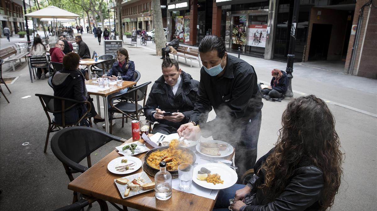 Un camanero sirve una paella en la terraza de un restaurante de la Rambla del Poblenou este pasado mes de abril.