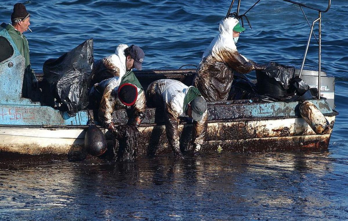 Pescadores retirando fuel del mar en A Cantareira.   | // CAMESELLE