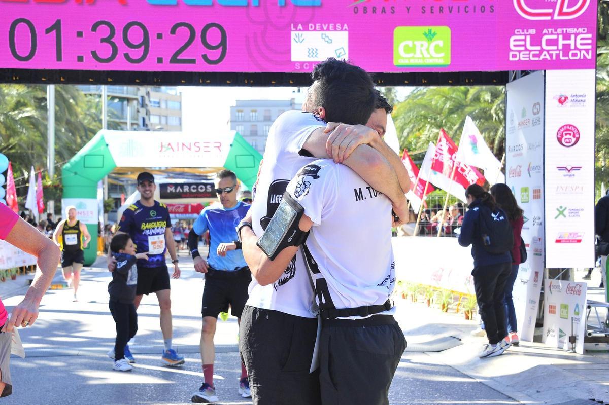 Dos atletas se abrazan tras cruzar la meta de la Media Maratón de Elche