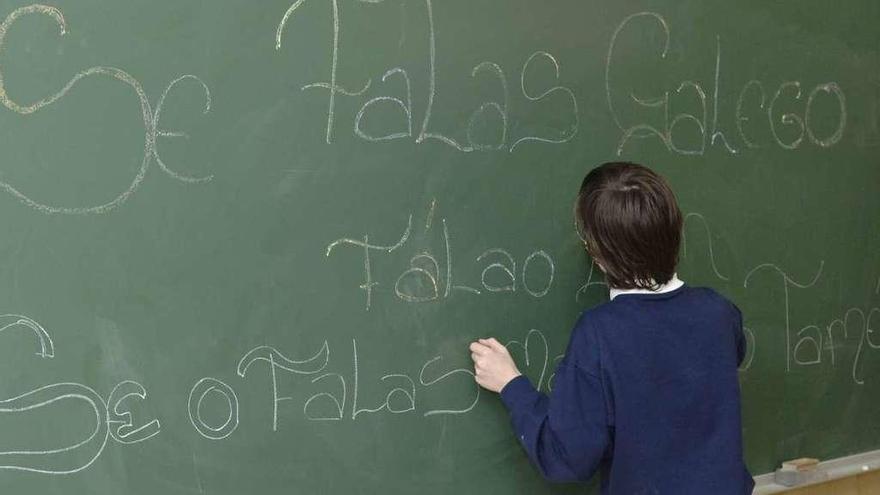 Un niño escribe en gallego en la pizarra de su clase.