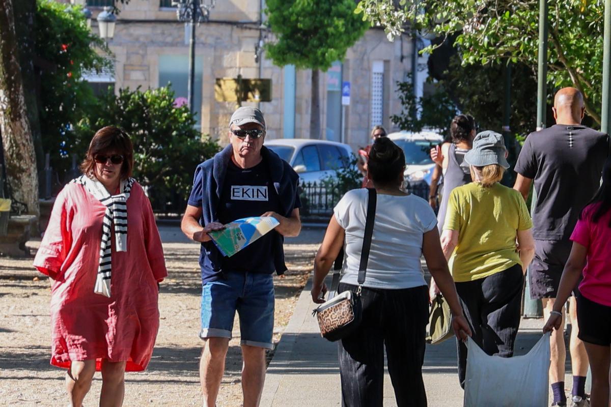 Una pareja pasea por Cambados con un plano turístico.